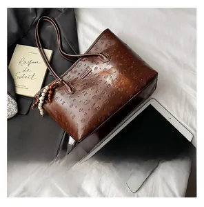 Detailed macro view of dark brown embossed leather tote with wooden bead keychain accessory