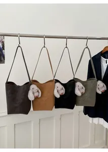 Detailed display of four retro bucket bags in brown, black, and green with plush charms