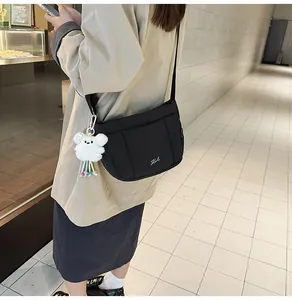 Détail du sac seau matelassé en nylon noir avec breloque ours en peluche et bandoulière réglable