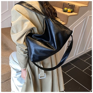 Detailansicht der schwarzen Hobo-Tasche aus weichem Kunstleder getragen mit einem Trenchcoat