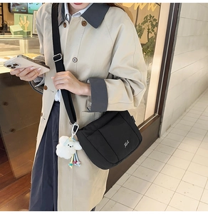 Détail du sac seau en nylon noir avec bandoulière large et breloque nuage en peluche blanche