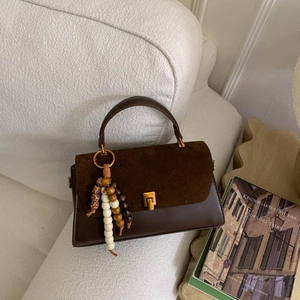 Détail d'un sac à main vintage marron foncé avec rabat en daim et gland à perles