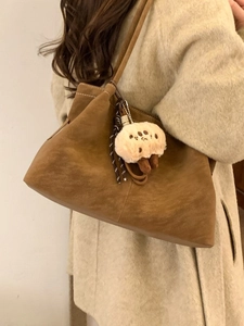 Retro brown matte suede tote bag with white stitching and plush charm shown on model