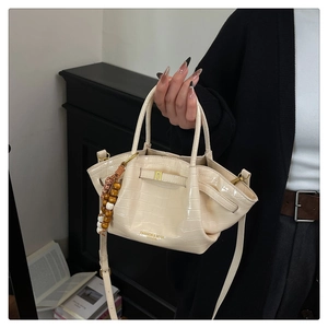 Dettaglio della borsa a secchiello beige con stampa coccodrillo e ciondolo di perline