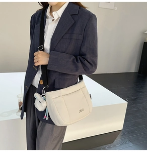 Détail du sac matelassé blanc cassé avec pendentif lapin en peluche et large bandoulière