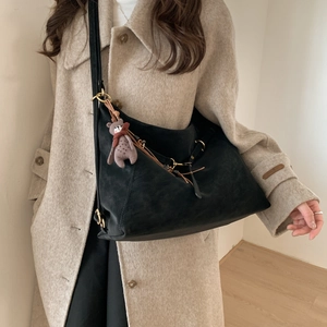 Detail der großen schwarzen Wildledertasche mit grauem Plüschbären am beigen Mantel