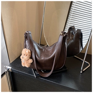 Close-up of deep brown hobo bag in matte PU leather with a cute plush bear charm