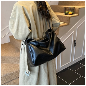 Detailansicht einer großen schwarzen Crossbody-Tasche aus PU-Leder am Modell im Trenchcoat