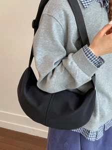 Minimalist black crescent crossbody bag with nylon fabric and wide strap on model