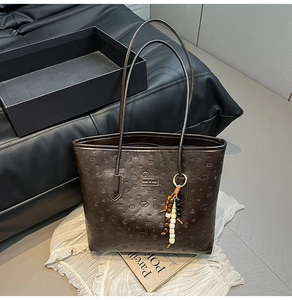 Detail of dark brown tote bag featuring embossed cartoon animals and beaded wood charm