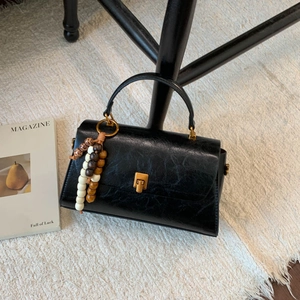 Détail de sac à main en cuir noir avec boucle dorée et pendentif de perles chic