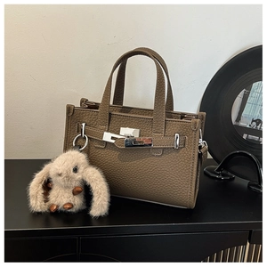 Detailed macro view of brown lychee grain leather tote with silver clasp and plush bunny charm