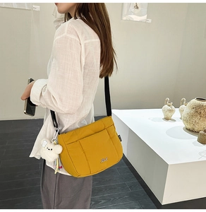Détail du sac seau en nylon jaune avec poches cargo et breloque ours en peluche blanc