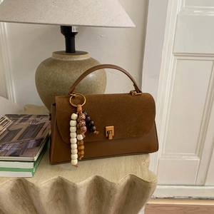 Détail du sac à bandoulière caramel avec patchwork en daim et breloques en bois