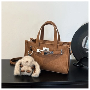 Detailed view of brown lychee grain leather tote with silver buckle and plush rabbit charm
