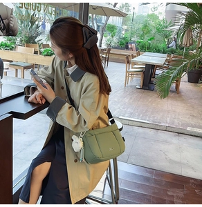 Détail d'un sac bandoulière matelassé vert clair avec charm agneau blanc et sangle noire