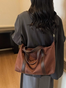 Retro brown suede tote bag with leather handles shown on a model in a warm indoor setting
