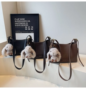 Three retro crossbody bags in black and brown with cute plush rabbit pendants on display
