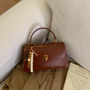 Détail du sac à main vintage en cuir marron avec fermoir doré et pampille en perles