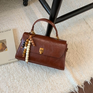 Vue détaillée du sac à main en cuir marron avec fermoir doré et breloque en perles rétro