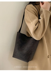 Detailed view of minimalist retro bucket bag with wide shoulder strap in dark leather