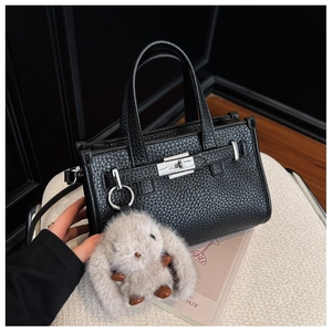 Detail of black pebbled leather tote bag with silver hardware and grey rabbit fur charm