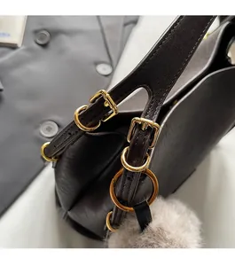 Detail of dark brown leather texture with gold-tone hardware and plush pendant bag
