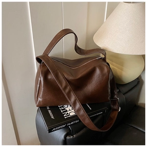 Detailansicht der dunkelbraunen Oversize-Ledertasche mit Vintage-Textur auf einem Sofa