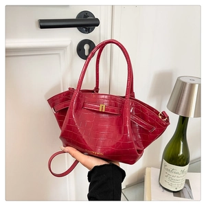 Dettaglio della borsa bordeaux con motivo a coccodrillo, fibbia dorata e logo moda
