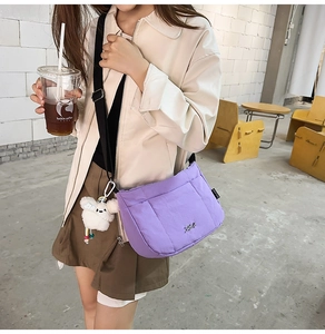 Détail du sac seau en nylon matelassé violet avec logo argenté et breloque lapin blanc