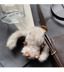 Close-up of a fluffy gray bunny plush charm with leather accents on a brown handbag strap