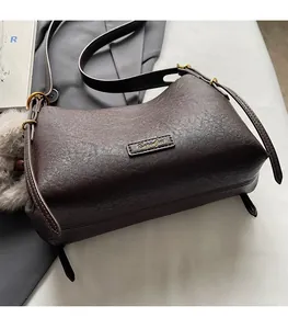 Detailed close-up of dark brown leather texture with golden hardware on a small square bag