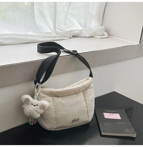 Détail du sac croissant matelassé beige avec bandoulière et breloque lapin