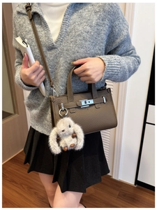 Close-up of brown litchi pattern leather tote with silver twist lock and plush rabbit charm