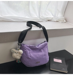 Détail de la bandoulière en nylon violet avec pendentif chiot blanc et sangle noire