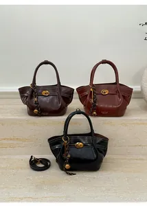 Detailed view of three leather bucket bags with vintage gold hardware and key pendants