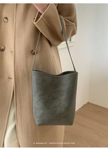 Detail of dark grey bucket bag showing vintage frosted leather texture on khaki wool coat