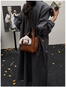 Détail du sac seau en cuir marron grainé avec un pendentif lapin blanc en peluche