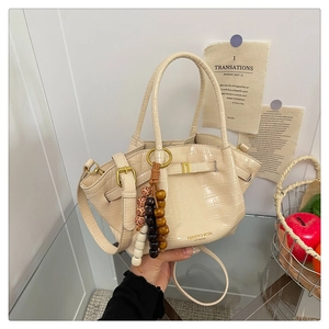 Dettaglio della borsa a secchiello beige coccodrillo con ciondolo in legno e logo oro