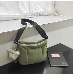 Détails macro du sac seau matelassé vert herbe avec breloque peluche et bandoulière