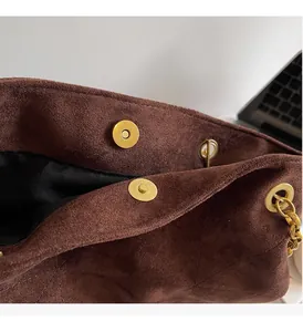 Détails macro des boucles dorées sur le sac cabas en daim marron avec matelassage