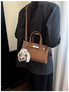 Brown lychee leather handbag with plush rabbit charm and adjustable shoulder strap