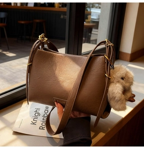 Detailed macro view of vintage brown leather bag texture with gold hardware and plush charm