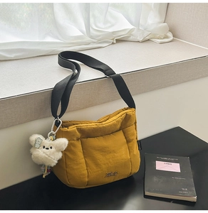 Détail du sac bandoulière matelassé jaune avec breloque chien peluche et sangle