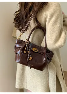 Detail view of brown leather tote bag featuring gold hardware locks and a stylish key charm