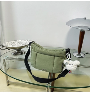 Détail d'un sac bandoulière matelassé vert olive avec large sangle et breloque chien peluche