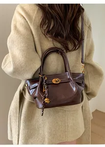 Detail of dark brown leather tote bag with gold twist lock and contrast stitching