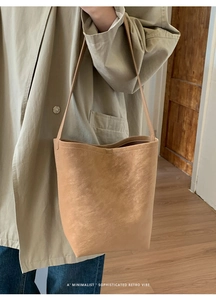 Tan retro bucket bag worn with a khaki trench coat for a minimalist aesthetic