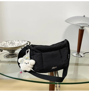 Détail du sac à bandoulière matelassé noir avec breloque en peluche et logo en métal doré