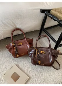 Close-up of vintage glossy leather tote bags with oval metal buckles and hanging charms
